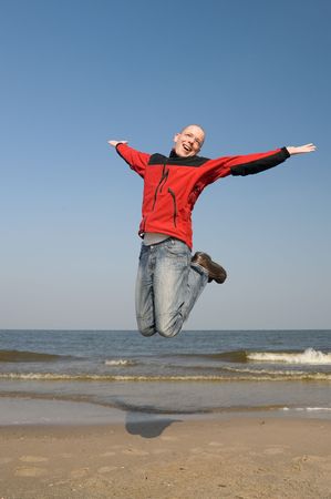 Young and happy man is jumping at the beachの写真素材