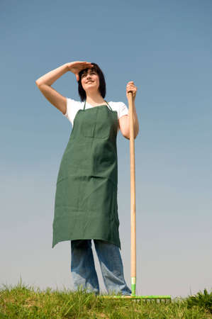 Young gardener standing in the meadow in front of blue skyの写真素材