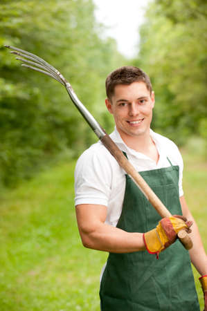 Young and smiling gardener with pitchfork