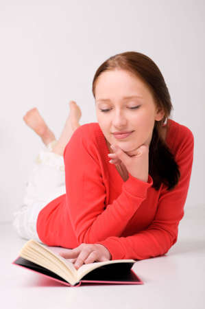 Young woman lying on the floor with bookの写真素材