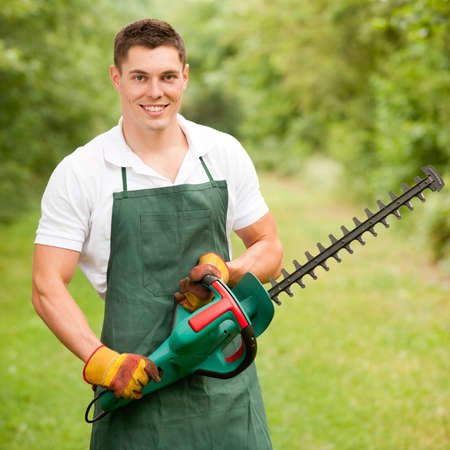 Young and smiling gardener with hedge cutterの写真素材