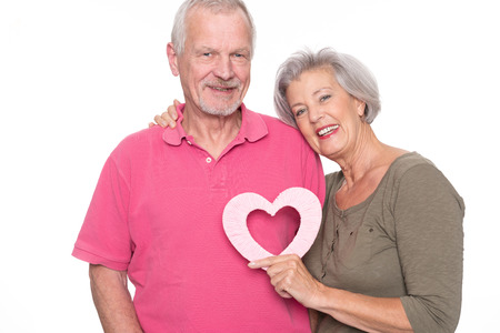 Senior couple with heart in front of white backgroundの写真素材