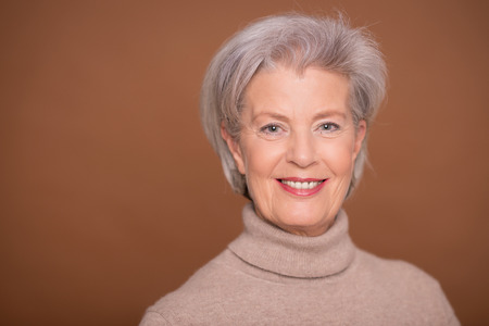 Portrait from a senior woman in front of brown backgroundの写真素材