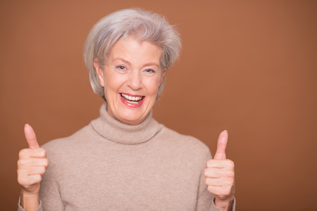 Portrait from a senior woman in front of brown backgroundの写真素材
