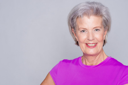 Portrait from a sportive senior woman in front of gray background