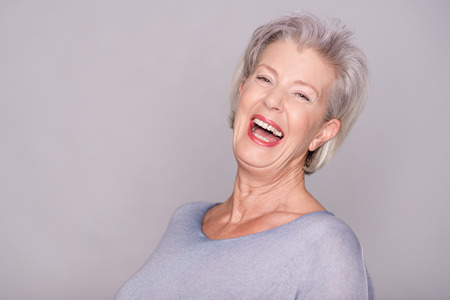 Portrait of a smiling senior woman in front of gray backgroundの写真素材