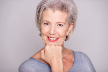 Portrait of a smiling senior woman in front of gray background
