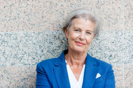 Happy senior woman in front of a wallの写真素材