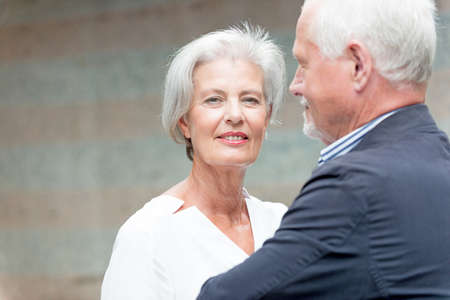 Smiling senior couple in front of a wallの写真素材