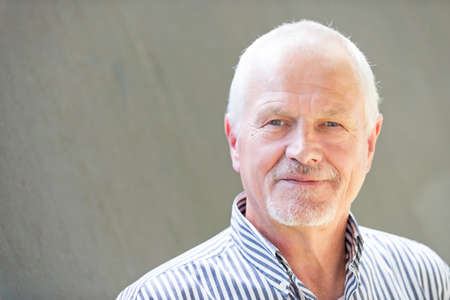 Senior man in front of a grey wallの写真素材