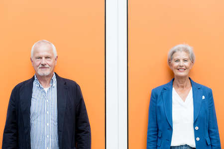 Happy senior couple in front of orange background