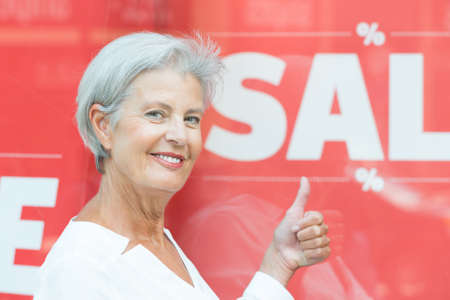 Senior woman in front of a sale signの写真素材