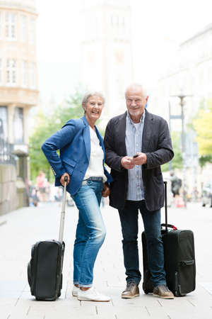 Senior couple with  suitcases and cellの写真素材