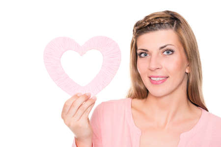 Smiling young woman with pink heart in front of white backgroundの写真素材