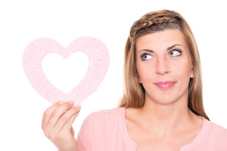 Smiling young woman with pink heart in front of white backgroundの写真素材