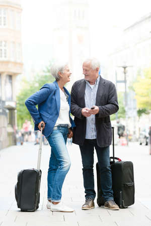 Senior couple with  suitcases and cellの写真素材