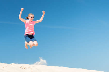Jumping young girl in front of blue sky