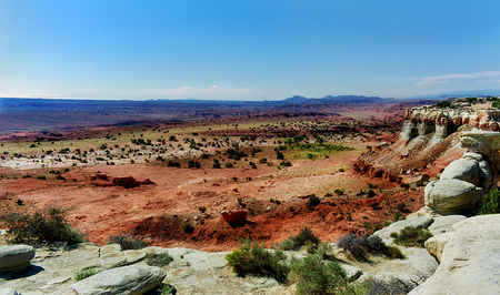 A vista of red and gray rocks with mountains in the background. The picture is colorful with reds and greens across the plains. The picture is reflective of distance, deserts, sky, plains, rock, mountains, heat, and landscape. Taken in San Rafael Salt Wasの写真素材