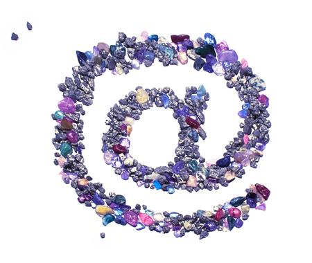 An at (@) symbol made from blue and black shiny rocks and gems. The picture is reflective of color,...