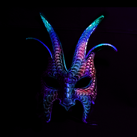 A colorful, scary halloween mask in blues and purples against a black background.の写真素材