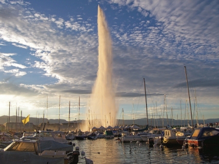Geneva - the fountain in the background of glowing clouds and a port for yachtsの写真素材
