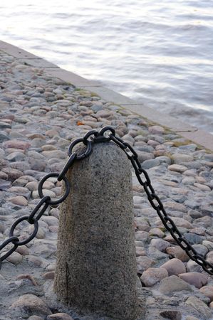 Old fence with a metal chain on the stone embankment of the riverの写真素材