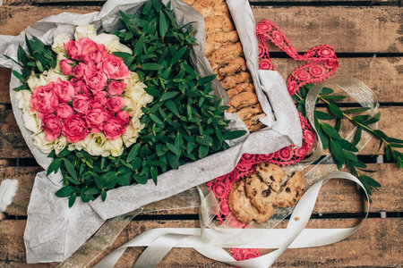 Box with flowers roses and biscuits on a wooden tableの写真素材