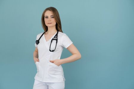White woman doctor in white clothes looks with a stethoscope on his neck on a blue background