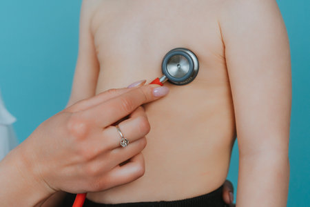 Woman doctor listens with a stethoscope to the lungs of a little boyの写真素材
