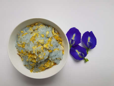 steam sticky rice with corn slices and mung bean above and Butterfly Pea flowers decoration.