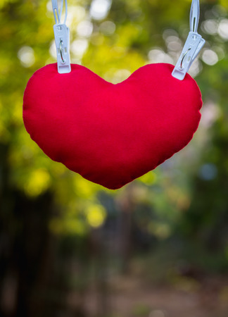 Red heart attached to a clothespin with nature backgroundの写真素材