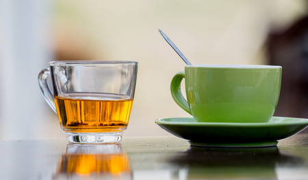 Tea glasses and green ceramic coffee mug on a wooden table.の写真素材