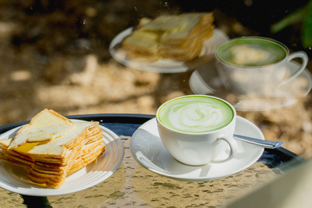 Hot green tea with biscuits on the table and a reflection mirror.の写真素材