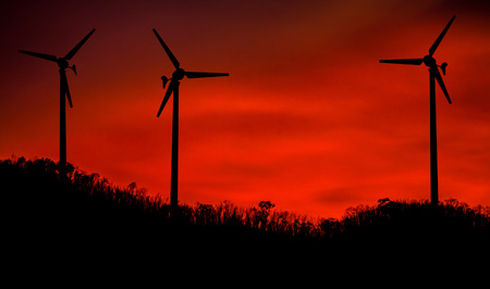 Wind Turbine for alternative energy on mountain silhouette at sunset. Eco power