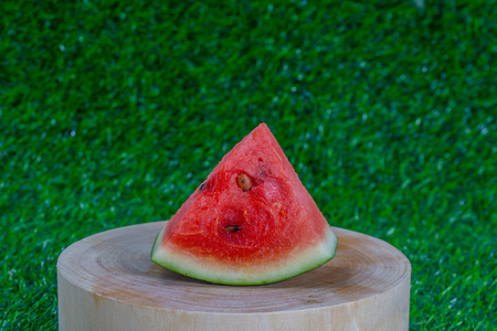 Slice of watermelon on wooden cheese board in green grassの写真素材