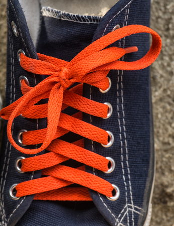 orange shoelaces in blue sneakersの写真素材