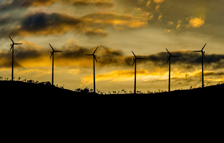 Wind Turbine for alternative energy on mountain silhouette at sunset. Eco powerの写真素材