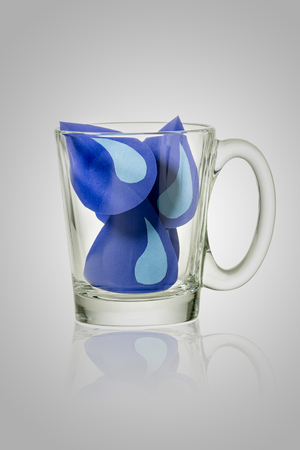 water drop paper cut in glass on gray background. File contains a clipping path.. Save water concept.の写真素材