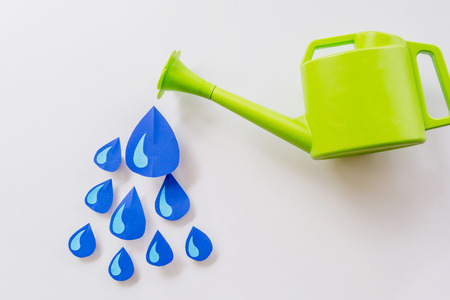 Concept green watering pot and and water droplets made of paper on a white background.の写真素材