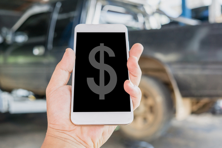 hand holding and using mobile smart phone calculate the cost of car repair.の写真素材