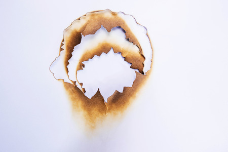 close up hole paper with edges burned on white backgroundの写真素材