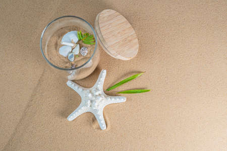 top view of sand beach with sea star and shells in glass jarの写真素材