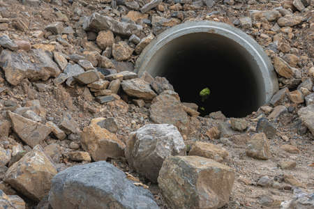 Concrete drain pipe under the ground and rocks