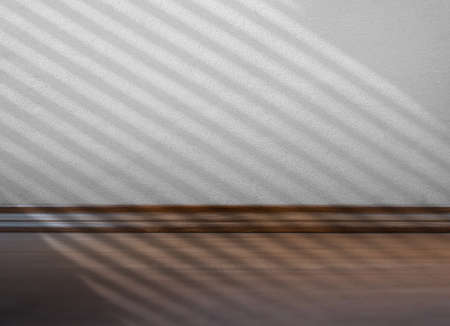 empty room with shadow batten of lath overlay on white concrete wall texture background and brown wooden floorの写真素材