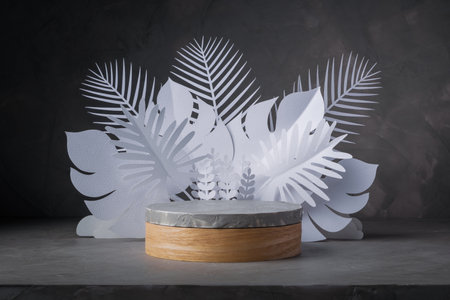 wooden and concrete cylinder shape podium stage decorate with white paper cut style elements of leaf for show product packaging and cosmetic on gray concrete wall background, copy space, empty podiumの写真素材