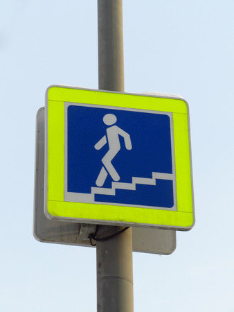City sign of the underpass. Coming down the stairs man on a blue background in a yellow frame.の写真素材
