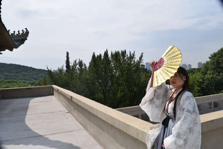 Woman in traditional attire with a fan on the roof.の写真素材