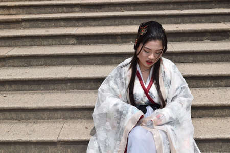 Japanese geisha in traditional kimono sitting on stairsの写真素材
