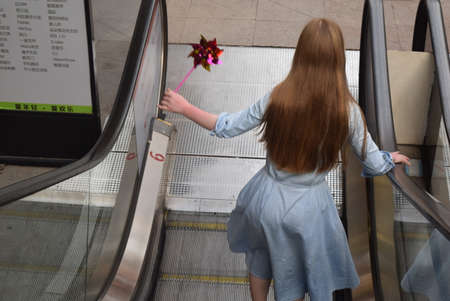 Young woman on an escalator. Back viewの写真素材