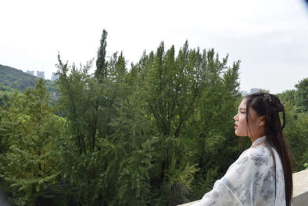 Young asian woman in a park looking at the view of the cityの写真素材